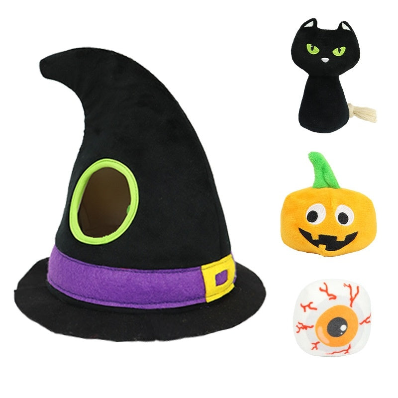 A black witch hat with a purple band, a green-eyed cat plush, a smiling pumpkin, and a white eyeball toy with red veins are displayed on a white background.