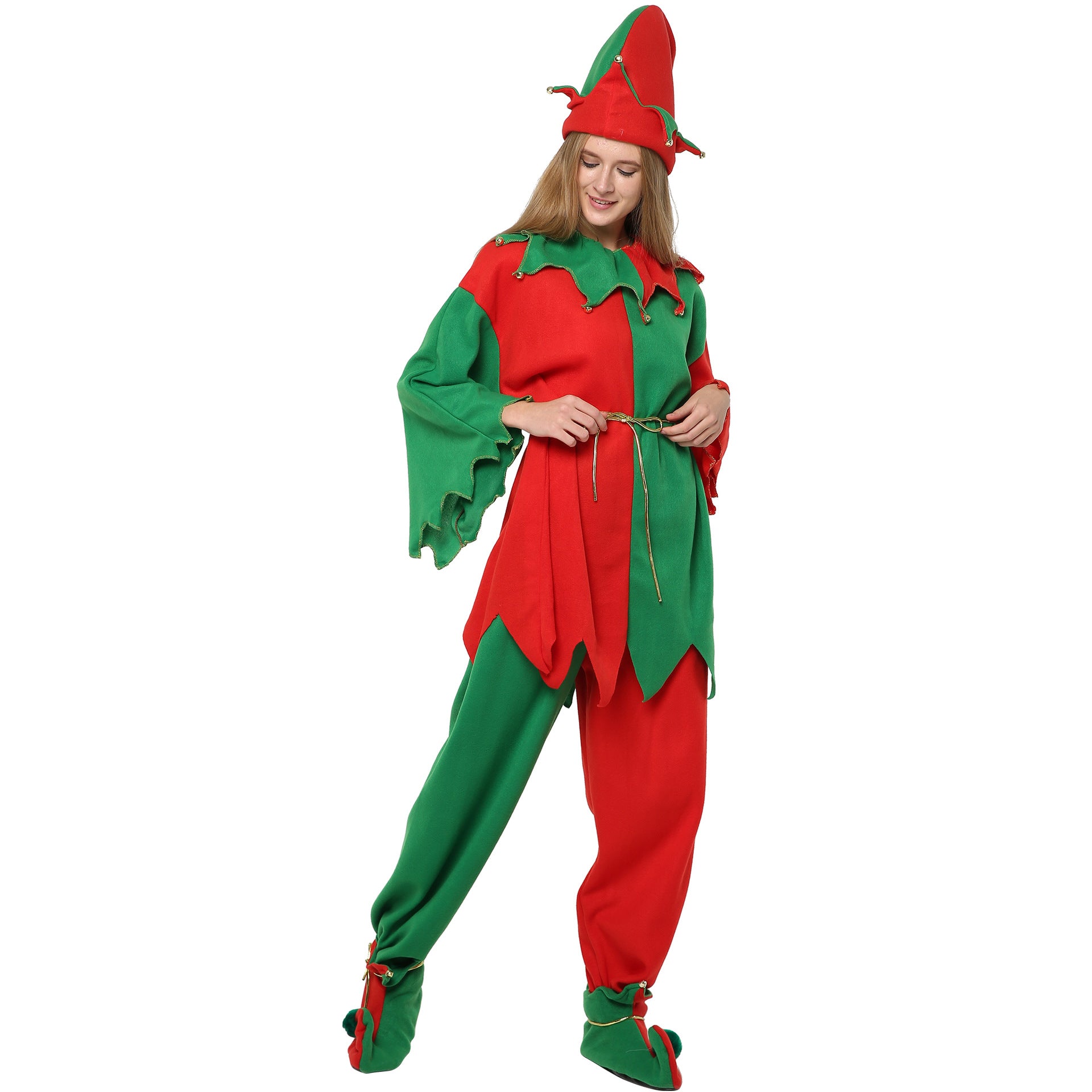 A person wearing a red and green elf costume with pointed hat and shoes, rope belt, and zigzag trim. They are smiling and standing against a white background.