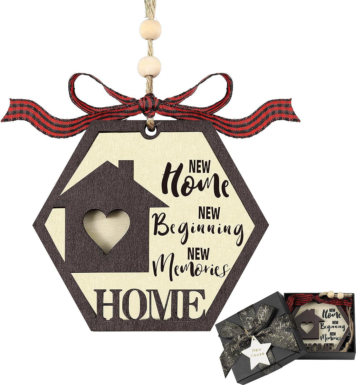 Hexagonal ornament with a house silhouette and a heart cutout. Text reads "New Home, New Beginning, New Memories." Topped with a red bow, shown alongside a gift box.