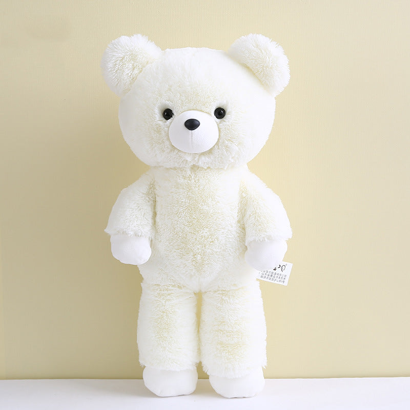 A fluffy white teddy bear with a cute expression, large black eyes, and a small black nose, stands against a light yellow background. A tag is attached to its arm.