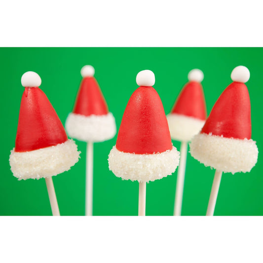 Festive cake pops shaped like Santa hats with red tops and white fluffy brims, set against a bright green background.